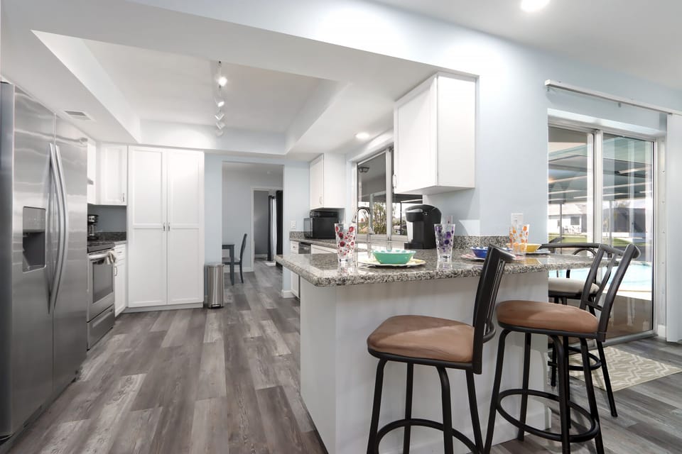 Cook up vacation meals with ease in the fully updated kitchen, featuring white shaker cabinets, stainless steel appliances, and a sunny breakfast bar just right for two