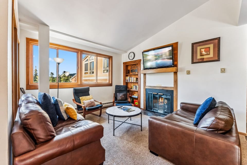 Living Room: 2 leather couches, 2 chairs, fireplace, TV, board games
