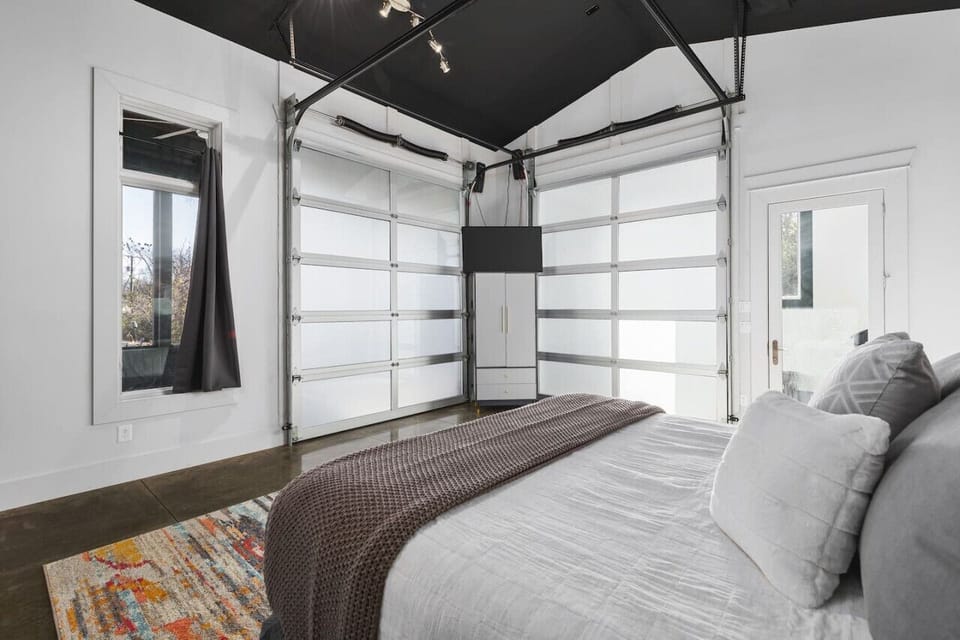 One of a kind primary bedroom with a king bed, Smart TV, and two garage doors you can open to lead to the patio space & hot tub.