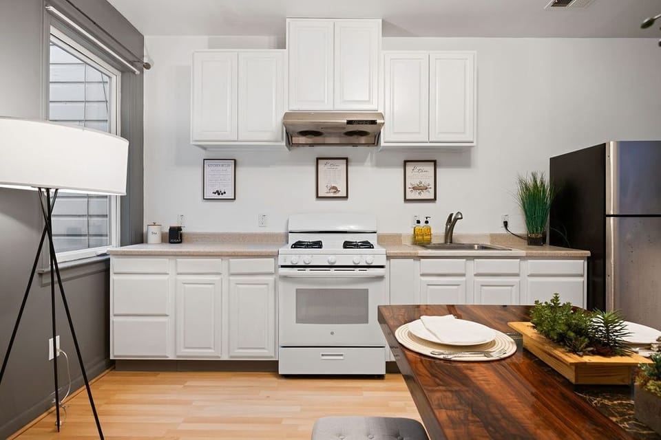 Kitchen with stainless steel fridge, stove, and wood table
