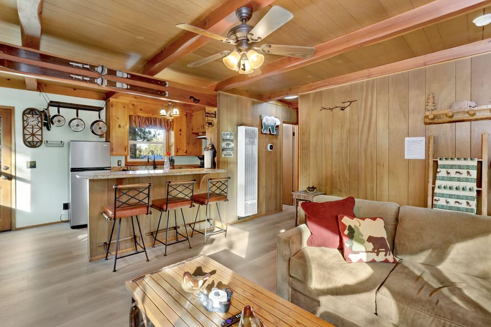 Cozy mountain living room with a stone fireplace, comfy seating, and smart TV—perfect for relaxing evenings, movie nights, and warm cabin vibes after outdoor adventures.