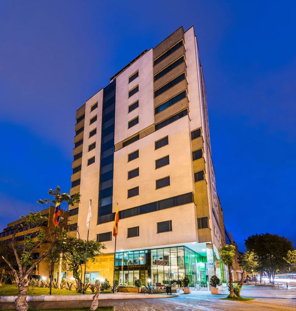Arrive to a sleek, well-lit hotel facade at dusk.
