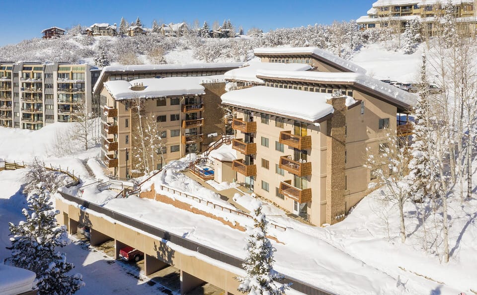 Nestled in a picturesque winter landscape, this alpine property offers mountain-style architecture and convenient ski-in access amid snow-covered trees and neighboring chalets.