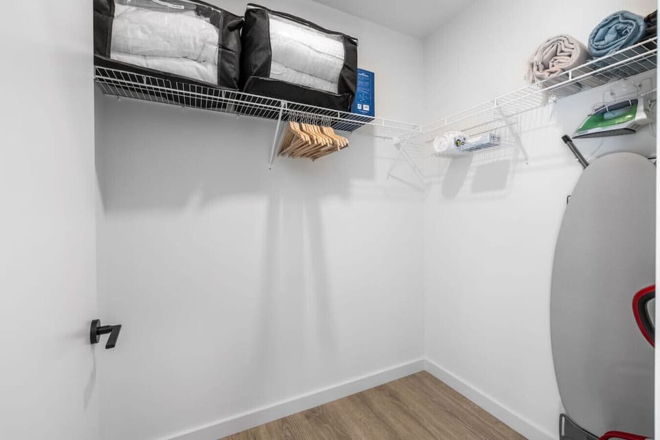 Walk-in closet with extra sheets, blankets, iron and ironing board