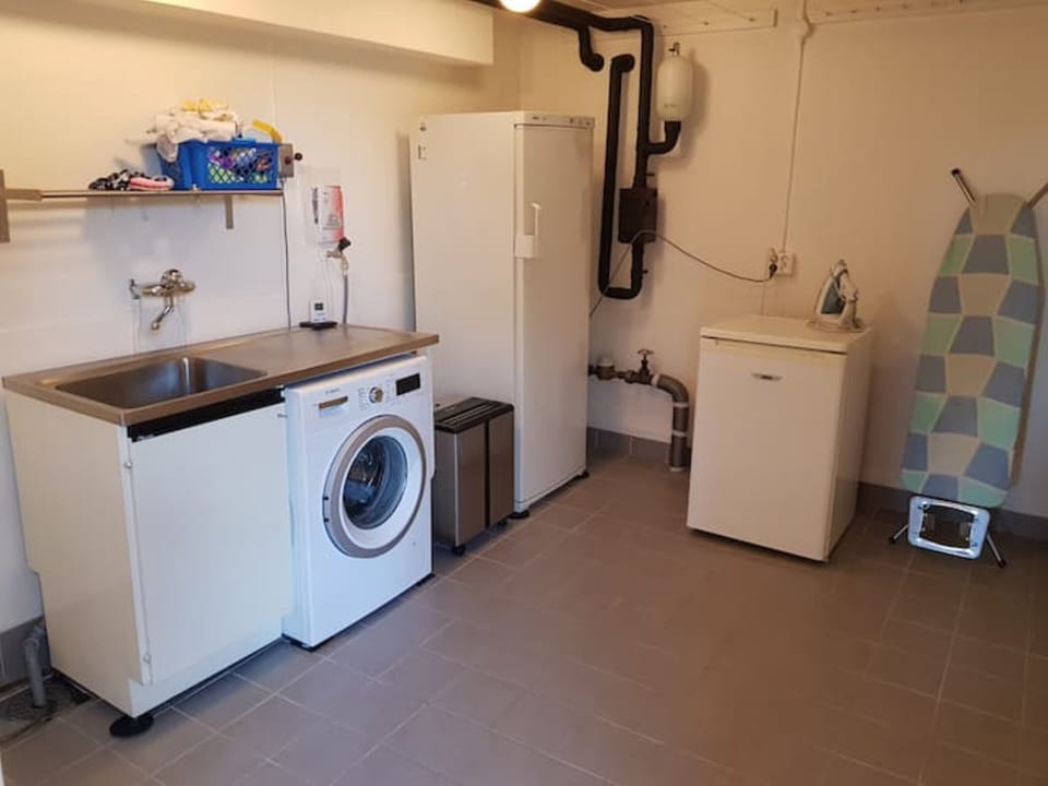 Washingroom with washing machine, ironing board and access to freezer. 