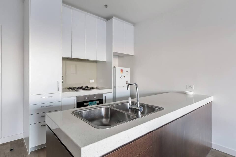 The kitchen is functional with ample bench space and storage, a dual sink, refrigeration, an oven, a stovetop and a range hood. 