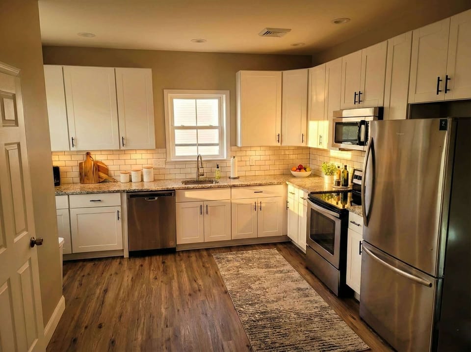 Kitchen with stainless steel appliances, white cabinetry, and tile backsplash.