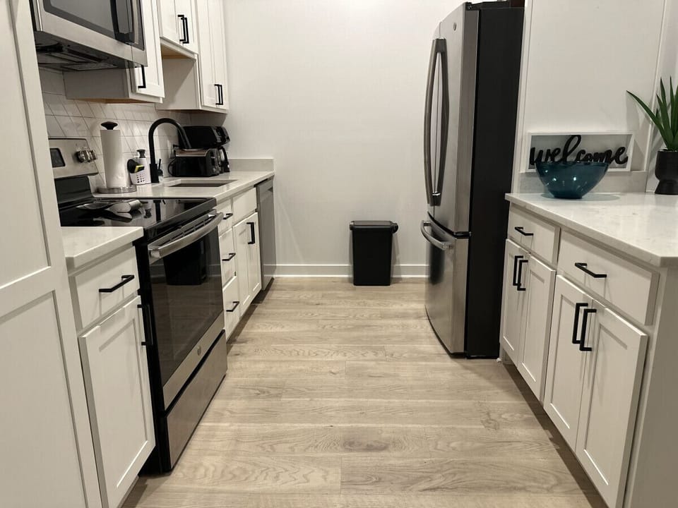 A modern and well-equipped kitchen with white cabinetry, stainless steel appliances, and coordinated countertops, creating a clean and inviting culinary space