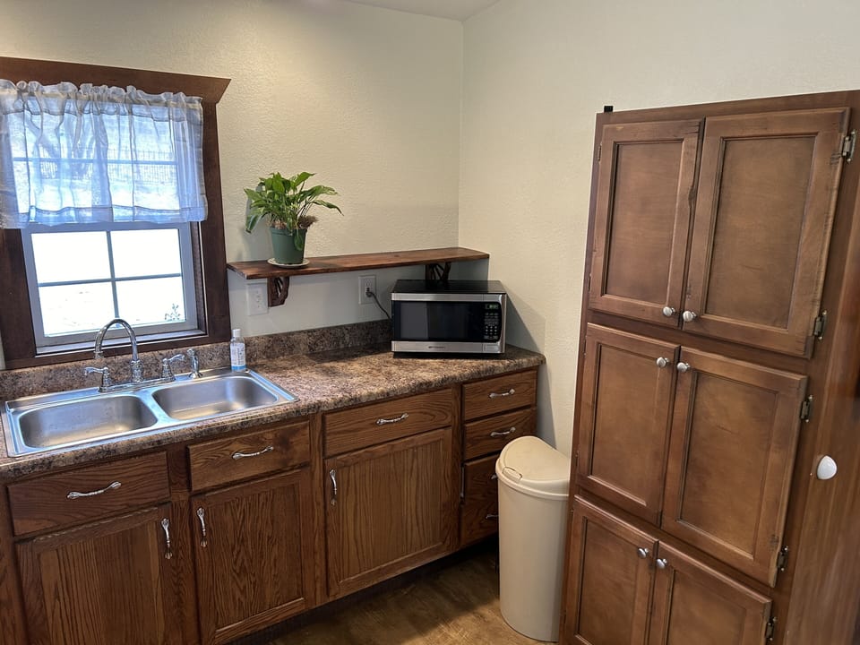Kitchen with cooking utensils, microwave and cabinet with china