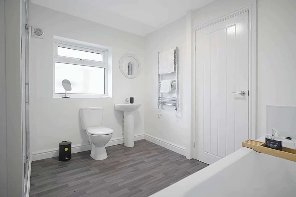 The bathroom benefits from a bath, an overhead shower, toilet and a sink. 