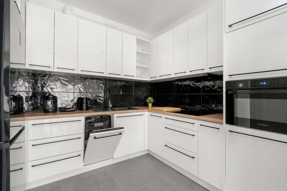 A luxurious kitchen with black marble backsplash and white cabinetry, giving a sleek and sophisticated look.
