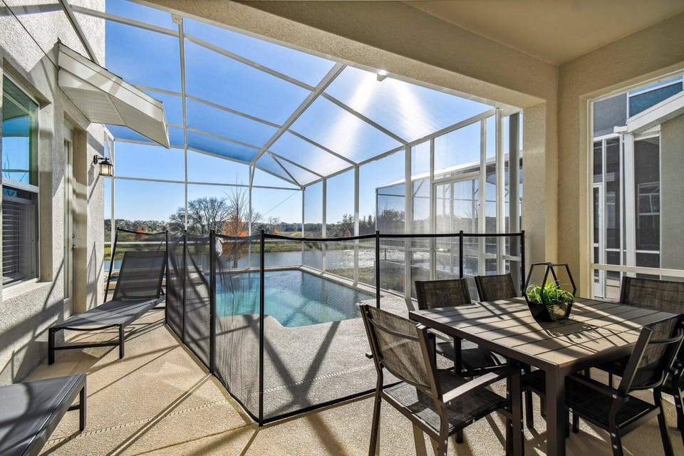 Bask in the warm sunlight on the spacious screened patio, where a stylish dining set invites alfresco meals. The serene pool glistens just beyond, framed by inviting outdoor seating that creates a perfect backdrop for relaxation.