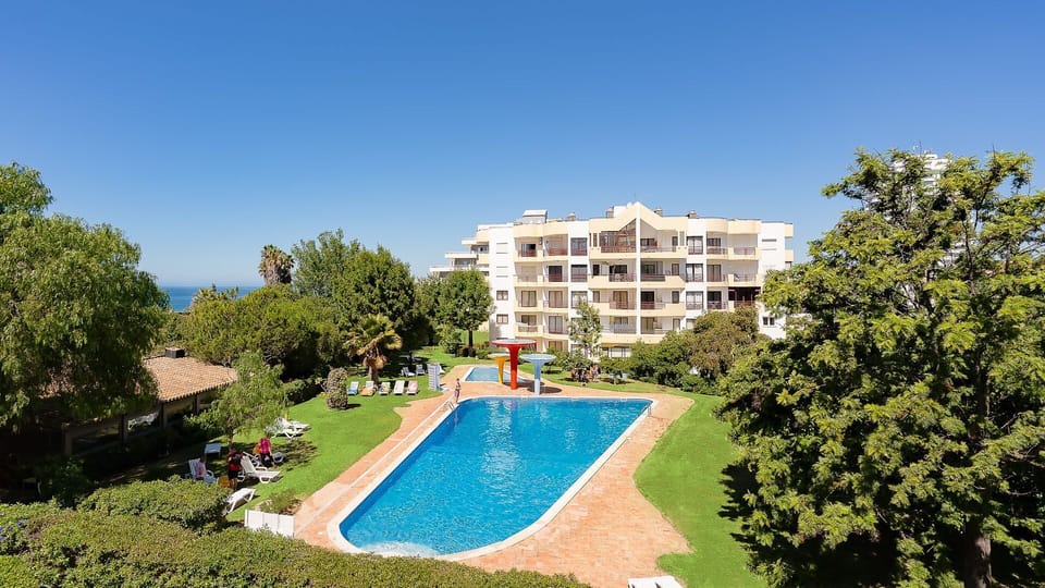 Dive into the sparkling blue pool, surrounded by lush green gardens, with the apartment complex offering a perfect sunny retreat.
#PoolArea #GardenView #LovelyStay