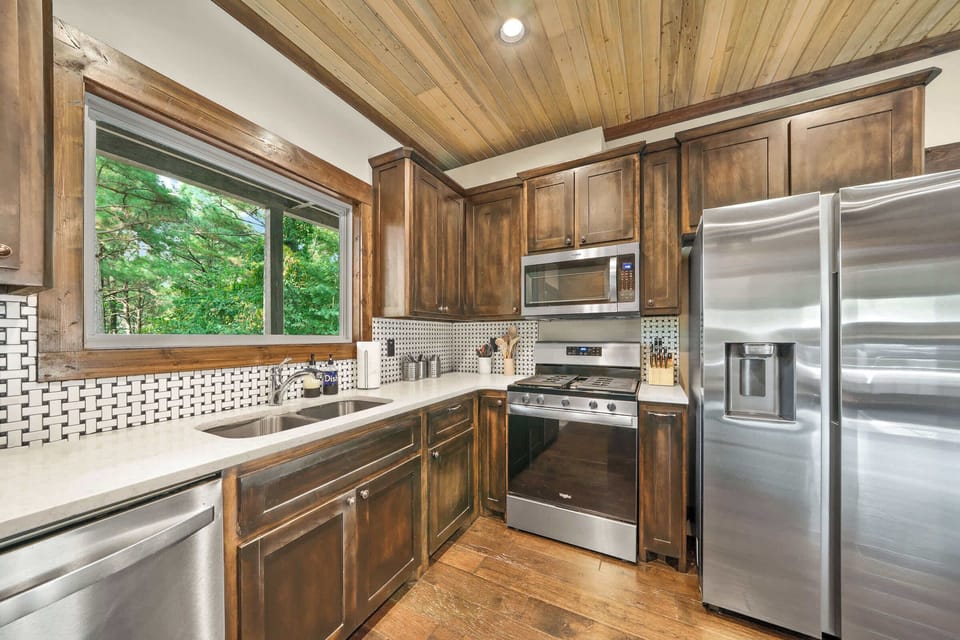 The modern kitchen features stainless steel appliances along with all cooking and dining supplies needed for a home-cooked meal.