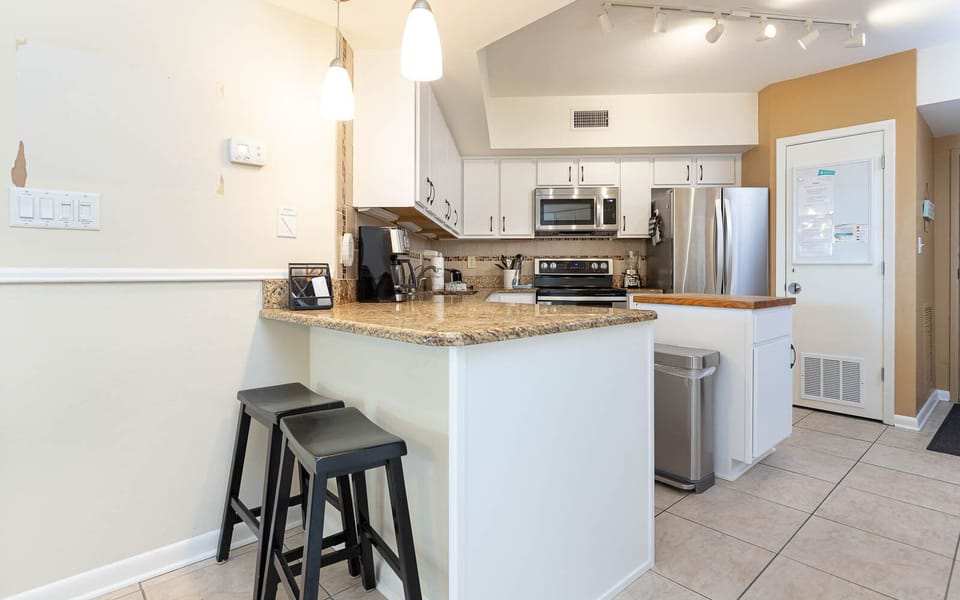This kitchen features sleek stainless steel appliances, granite countertops, and a cozy breakfast bar for casual dining