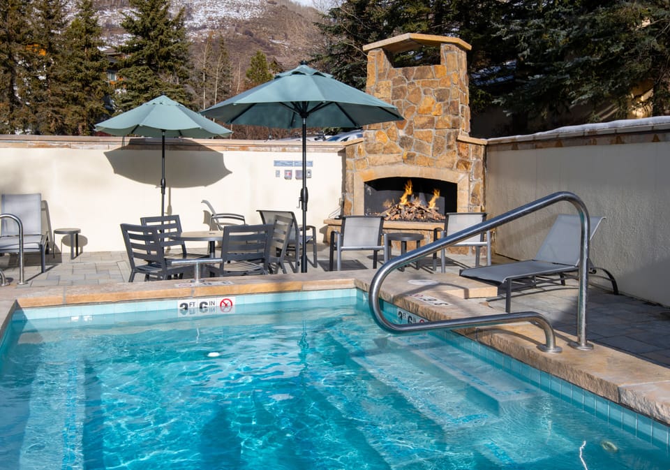Shared Pool and Hot Tub Area - Outdoor Fireplace with Dining Tables and Sun Loungers