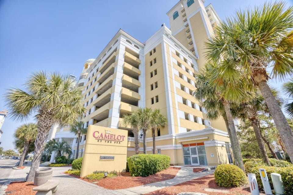 Streetside view of Camelot by the Sea Resort in Myrtle Beach featuring the oceanfront high-rise tower and resort entrance in a prime downtown location just steps from the beach, Myrtle Beach Boardwalk, restaurants, shops, and attractions.