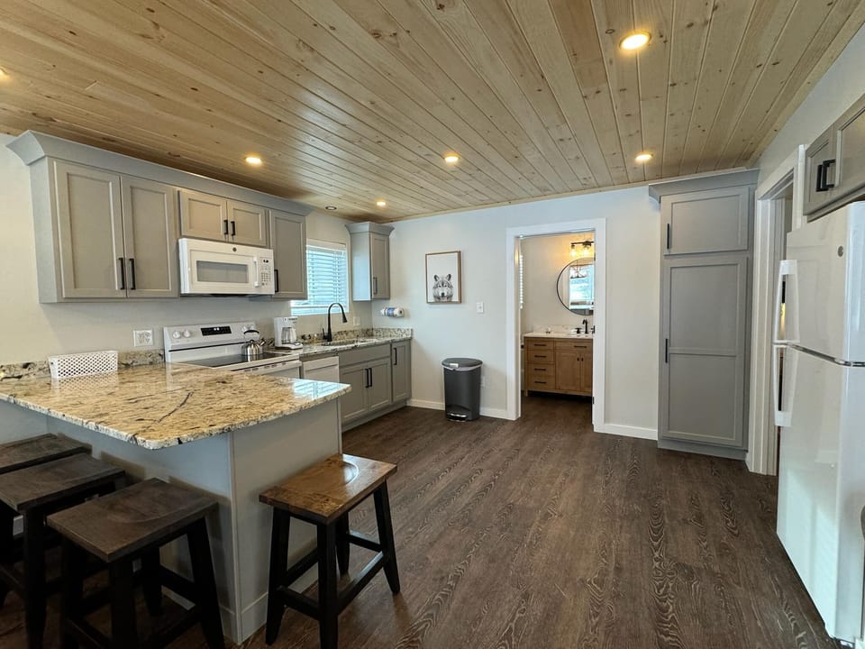 Fully equipped kitchen with a stove, microwave, toaster, and bar stools