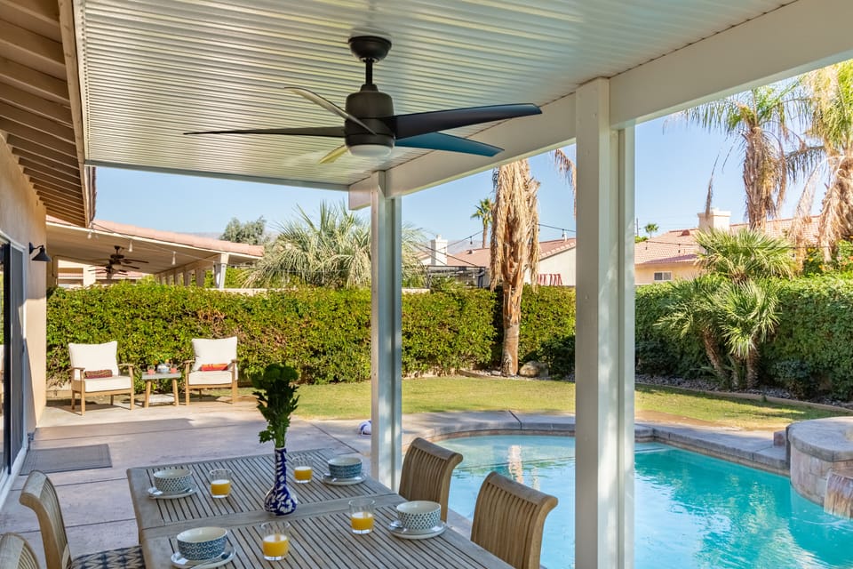 Covered patio has a dining table and fan for airflow.