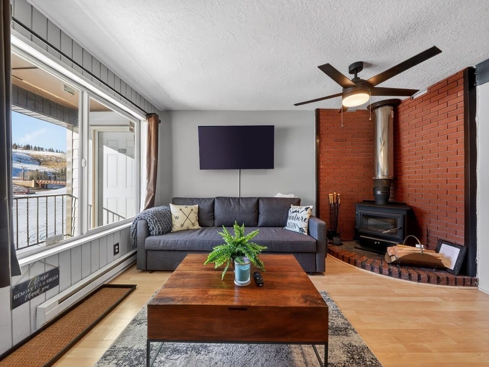 Unwind in your cozy living space with plush seating, warm fireplace, and mountain views through large windows.