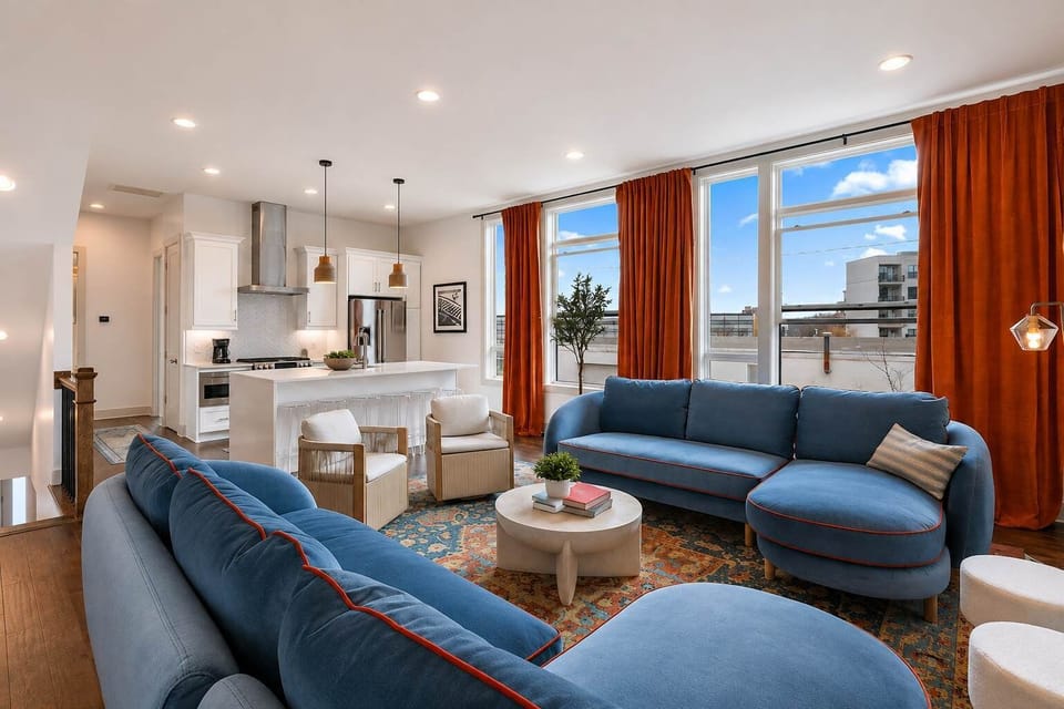 Sun-filled living room with plush blue sofas and skyline views, perfect for relaxing and entertaining.