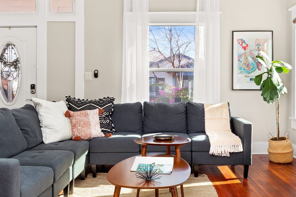 A symphony of relaxation: this living room, adorned with a TV, cozy sofa, side table, and a window to let the outside in