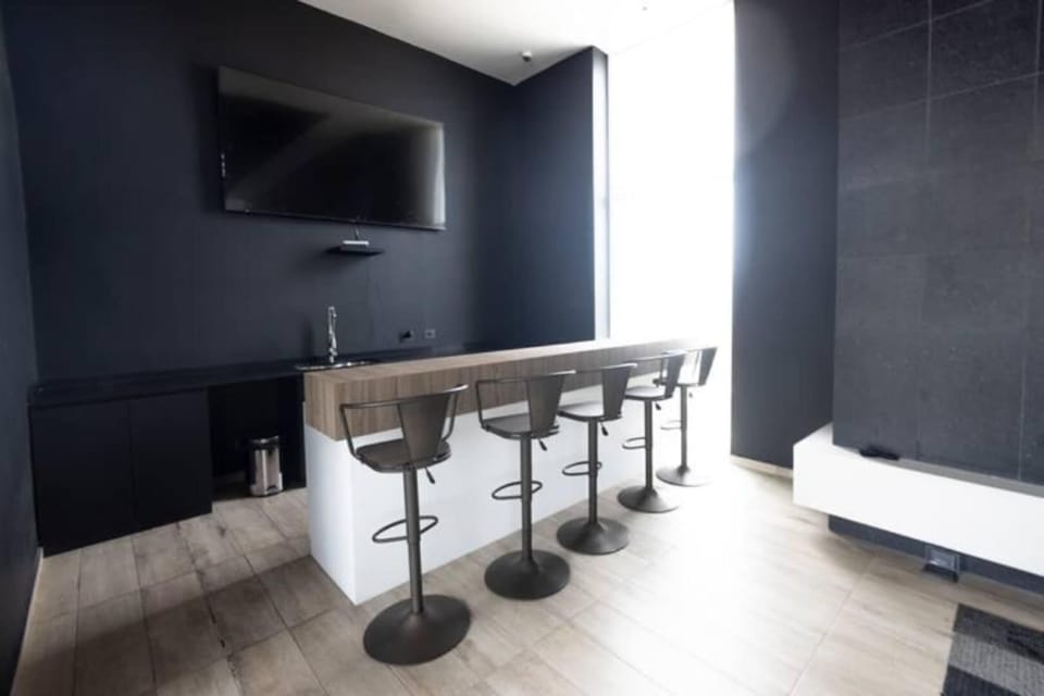 Enjoy a sleek and modern bar area perfect for relaxing or entertaining, complete with a wall-mounted TV and ample seating.