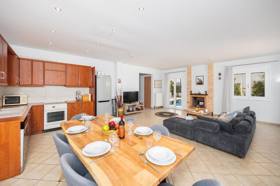 Open-plan living room with sofa, dining area, kitchen, ornamental fireplace, A/C, WiFi internet, and satellite TV