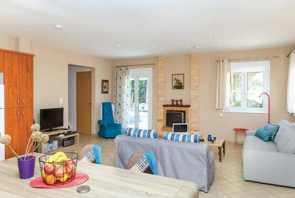 Open plan living room with comfortable sofas, ornamental fireplace, TV, patio doors, 