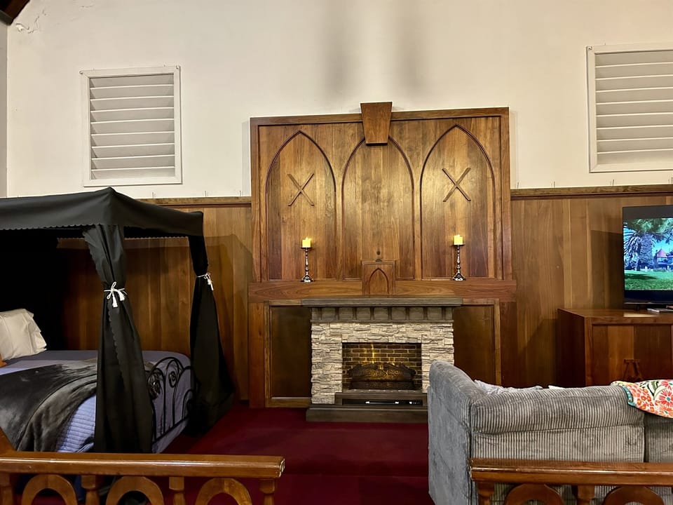 Pull back the curtains and let the fireplace glow — you're sleeping under a 130-year-old altar tonight, and there's no other bedroom on earth that looks like this.