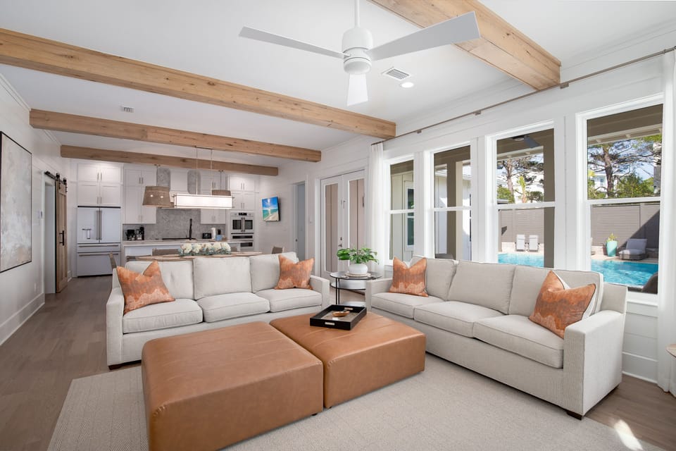 Unwind in this stunning open-concept space where natural wood beams frame your relaxation. Sink into plush sectional seating with pool views streaming through floor-to-ceiling windows.