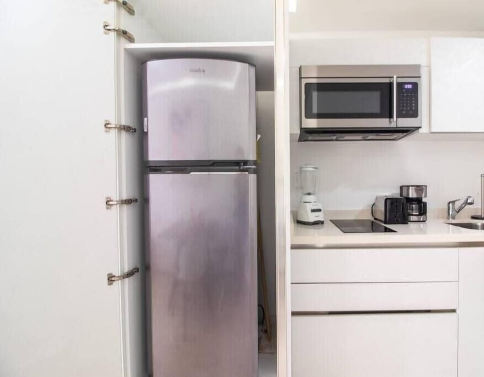 A fully equipped kitchenette with a fridge, microwave, and coffee maker.