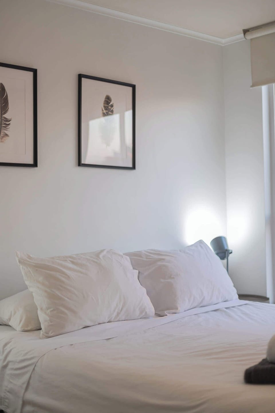Relax in this serene bedroom with soft lighting and elegant feather artwork, perfect for a restful night's sleep.