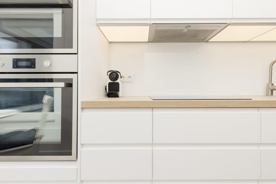 A modern kitchen with built-in appliances, white cabinets, and minimalist design, offering a clean and functional cooking space.
