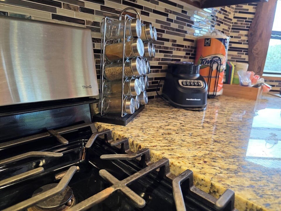 Full kitchen with granite counters, gas range, stainless dishwasher, and tile