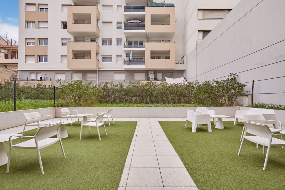 Tranquil green corner with white chairs surrounded by vibrant plants offering a peaceful spot to unwind.