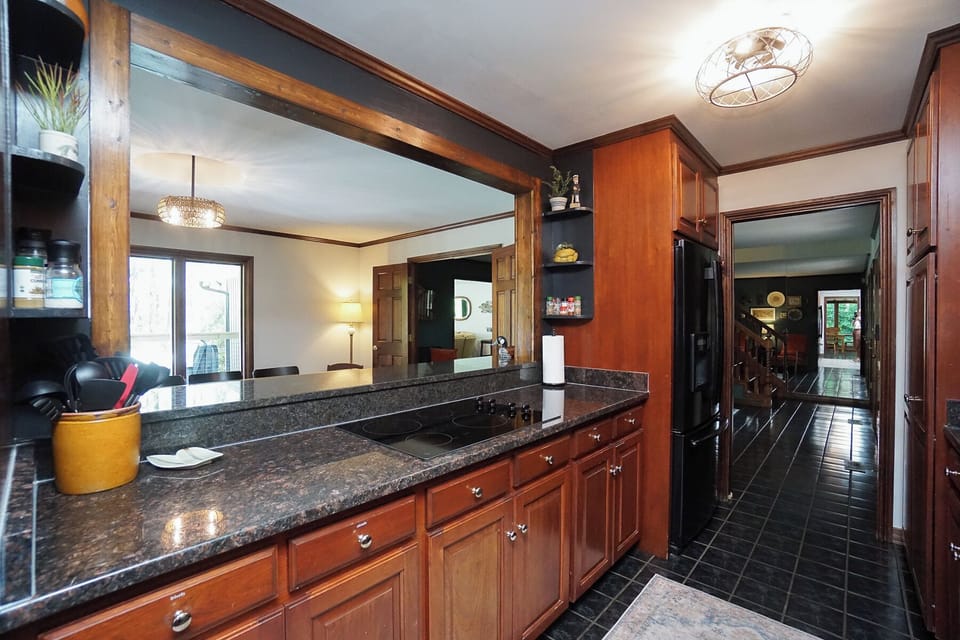 Kitchen passthrough views the dining room, hot tub, fire pit, grill, and lake.