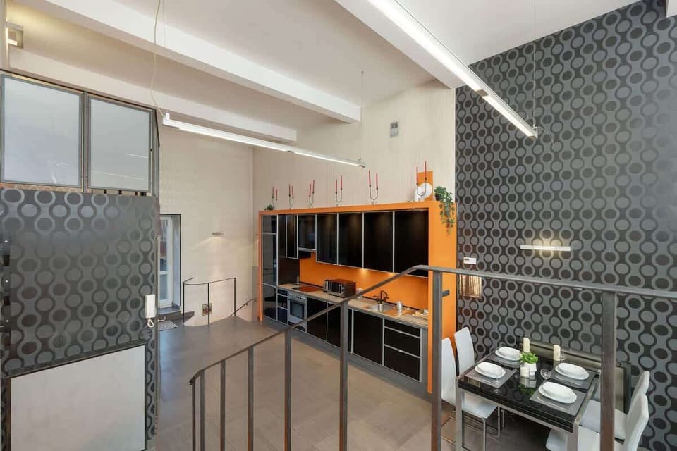 A stylish living room with a black and orange theme, featuring a unique wall design and sleek furniture.
