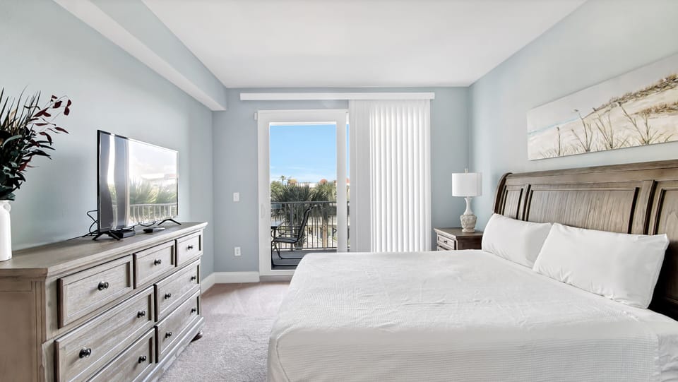 bright bedroom with balcony access and coastal views