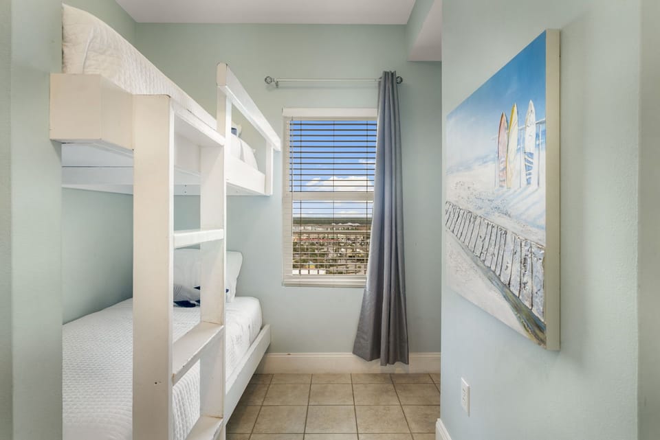 Cozy bunk bed room with a window view and soft blue walls.