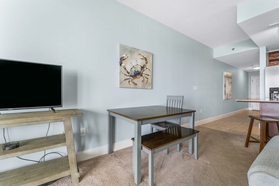 Compact dining area with coastal artwork and a modern television setup