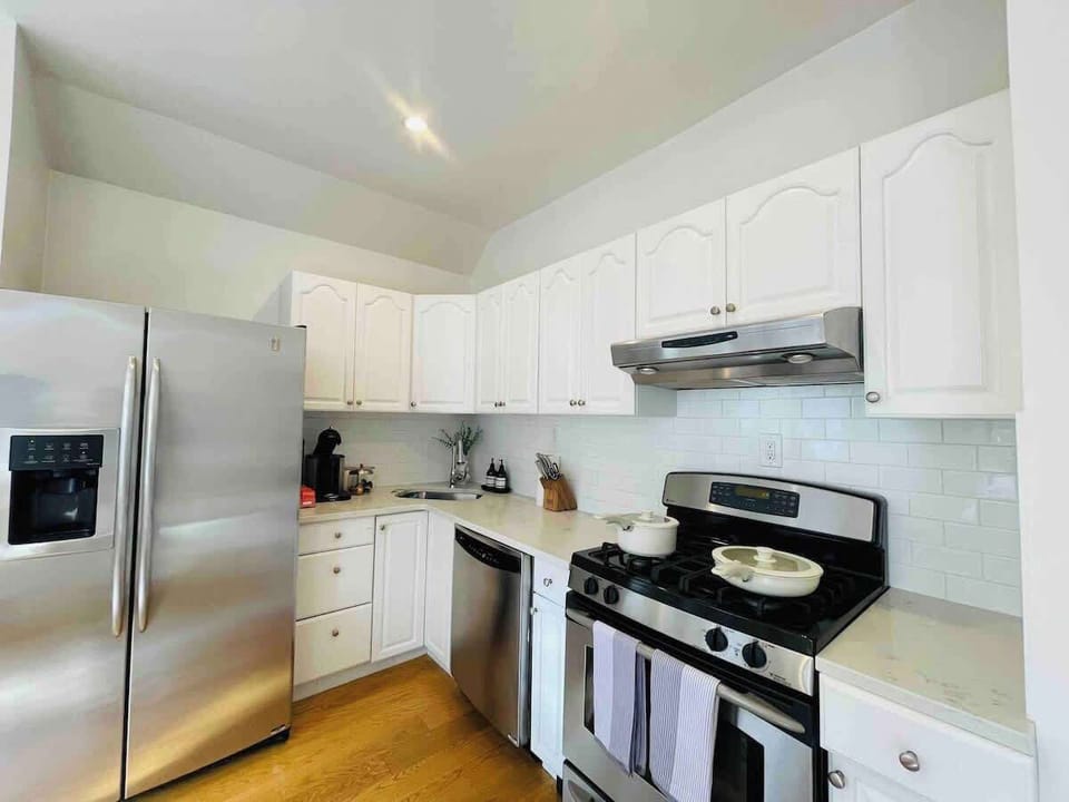 Full kitchen with pans, pots, Nespresso coffee and pods, knives, cups, bowls and plates, silverware, dishwasher, refrigerator, oven.