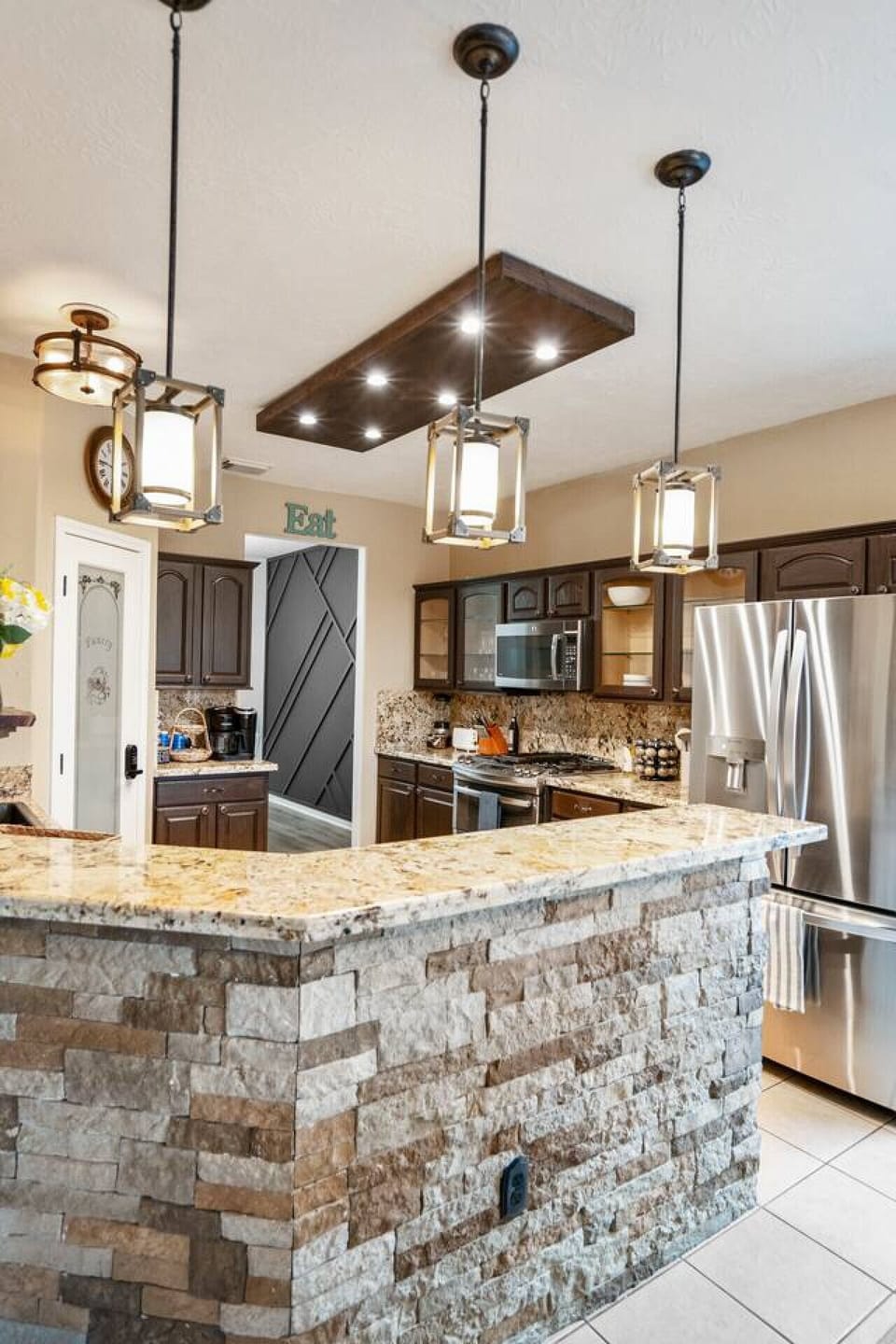 Modern kitchen with granite counters, stone bar, and stainless steel appliances