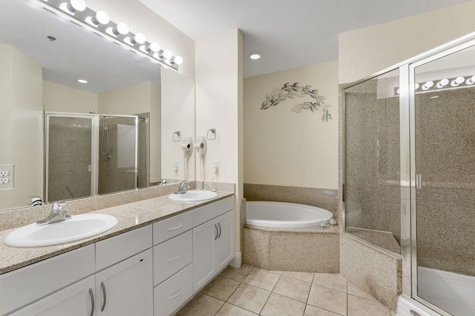 spacious bathroom featuring a double vanity, soaking tub, and separate glass-enclosed shower