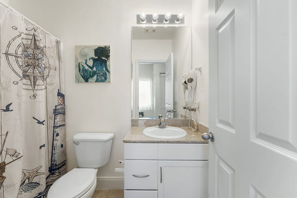 Compact bathroom with a nautical-themed shower curtain and modern fixtures.