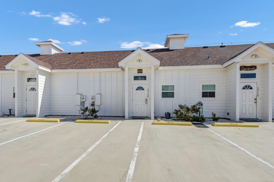 Modern white townhomes with dedicated parking spaces create an inviting arrival experience for your stay.