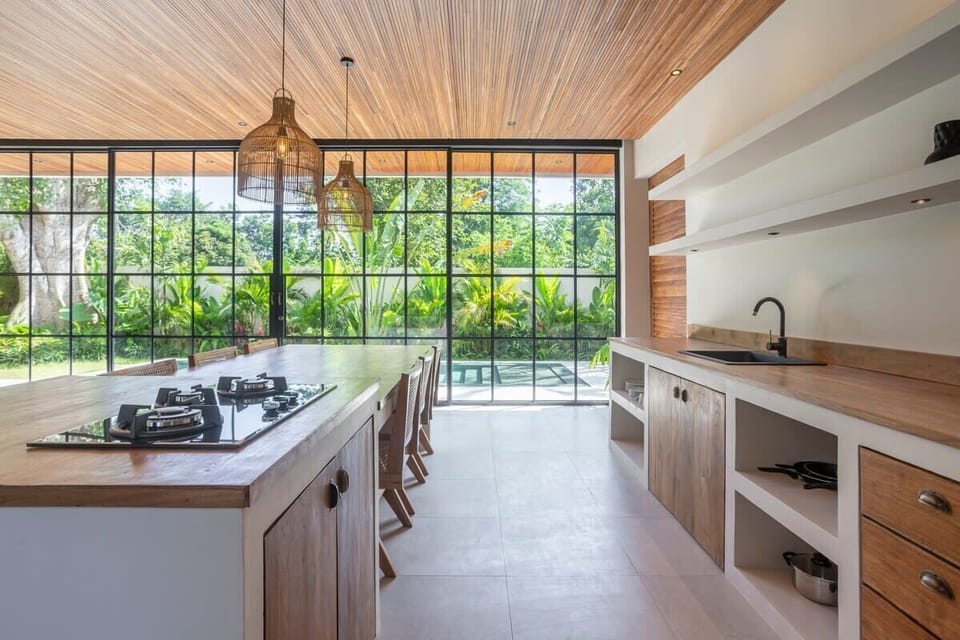 Fully equipped kitchen with a stove (3 burners), oven, pots, cutting board, knives, plates, and glasses
