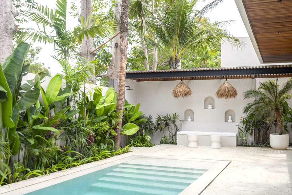 A swimming pool with lounge, an outdoor shower, and a lush garden