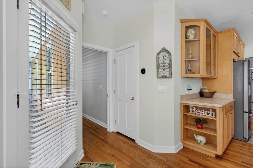Your bright kitchen welcomes you with warm wood cabinetry, coastal charm, and plenty of natural light streaming through plantation shutters.