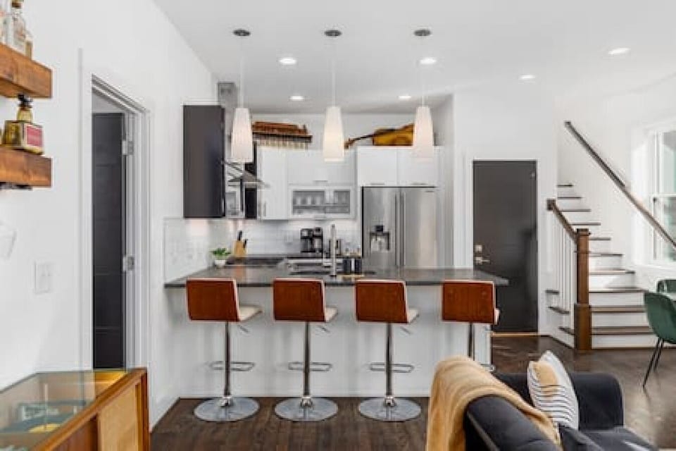 Open floor plan with a vintage record player, dining table, living room with a Smart TV, and seating for four at the kitchen counter.